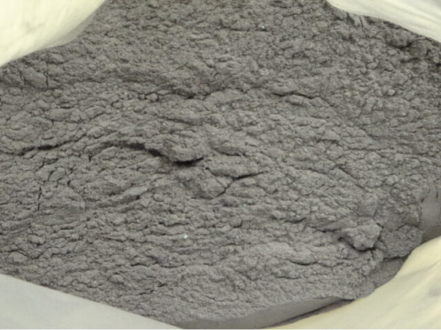 真鍮滓を処理する過程で発生するトビ粉。見た目はセメントの粉のように非常に細かく、粉が飛散することから扱いは難しい。但し、銅品位は１５％前後あるものが多く含水率も低いため、原料として有望。